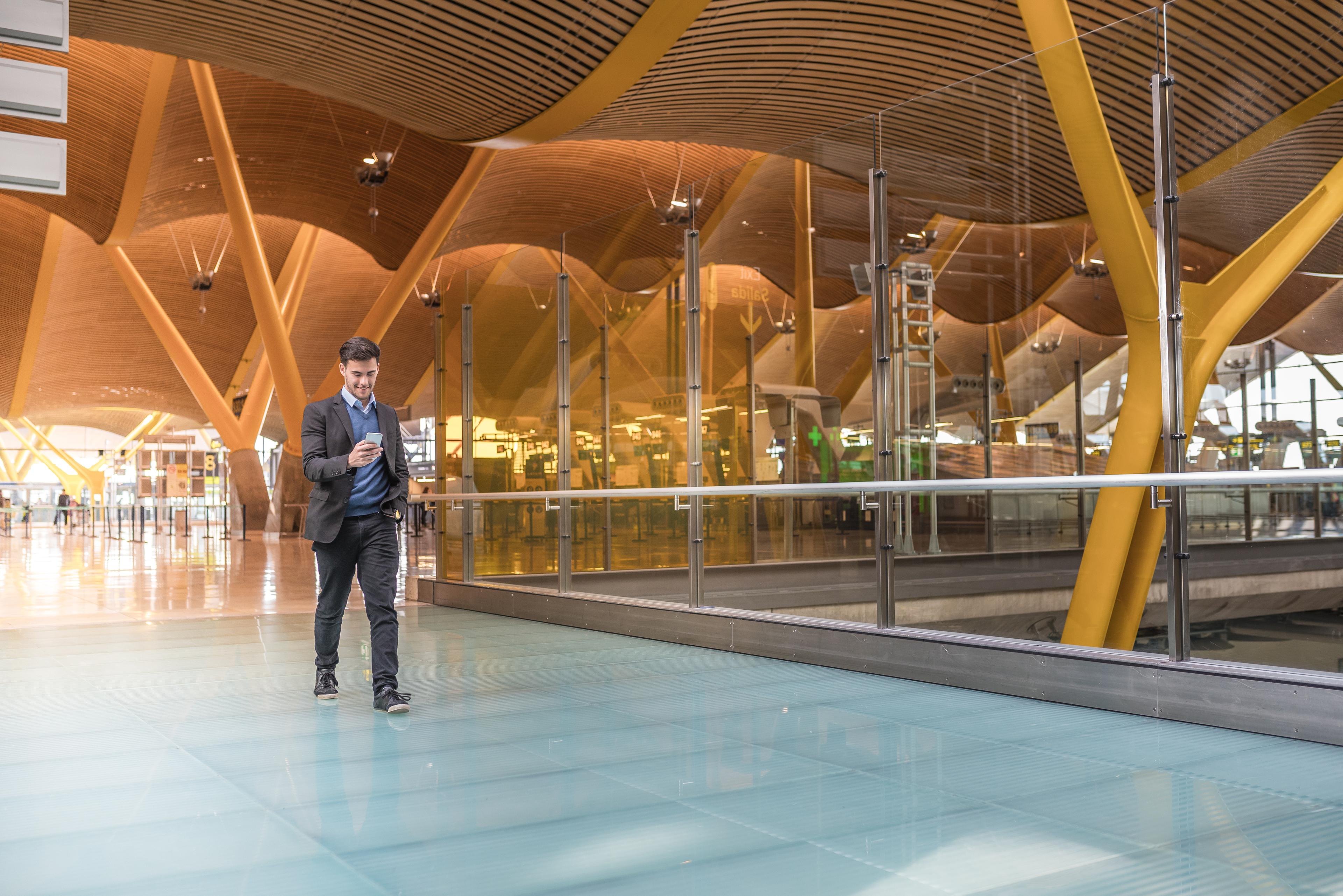 man looking at the phone and wolking in airport